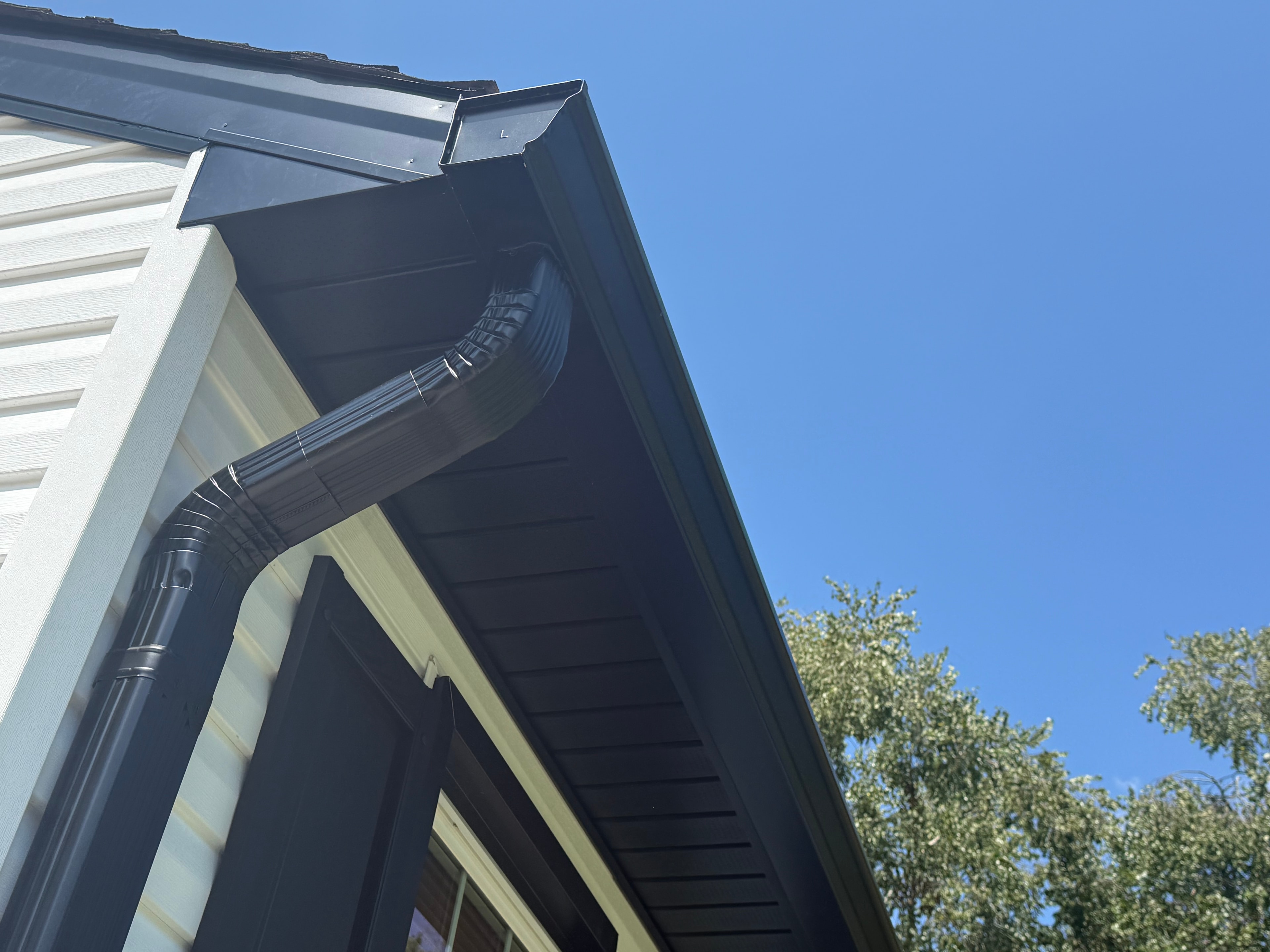 Black seamless gutters with downspout on residential home